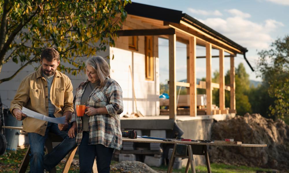 2 people standing in front of construction looking at building permit