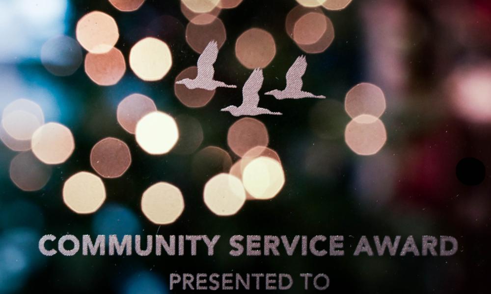 close-up of a glass community service award, with twinkling lights in the background