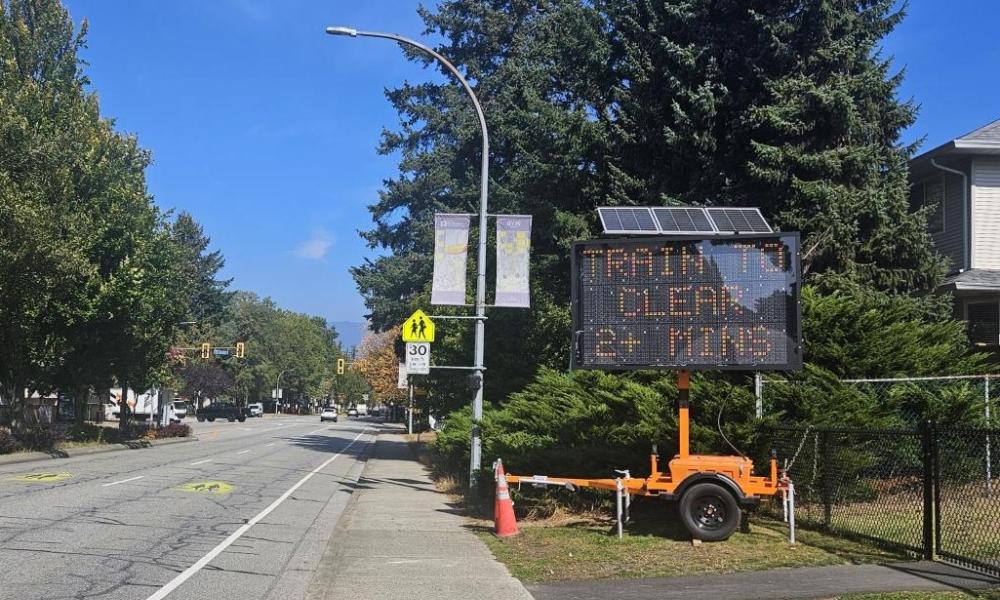 sign on Harris Road that says "train to clear 2+ mins"