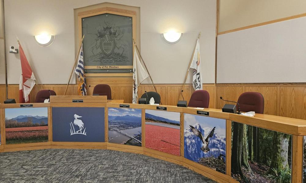 Wrap-around desk in Council Chambers with empty seats