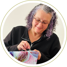Image of artist, Jennie sewing an art piece